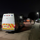 Police officers and police van outside in the dark