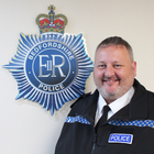 Garry Forsyth stood next to the Bedfordshire Police crest