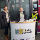 Three people stood behind a table with a Safer Streets sign