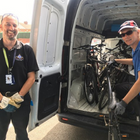 Two men stood next to a van, one loading a bike into the van