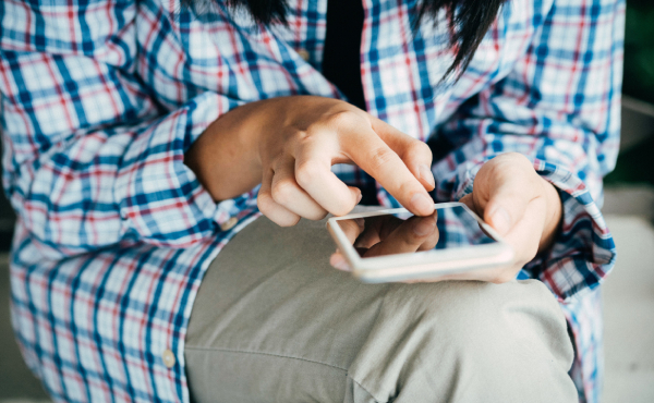 Person resting a phone on their knee and pressing the keypad