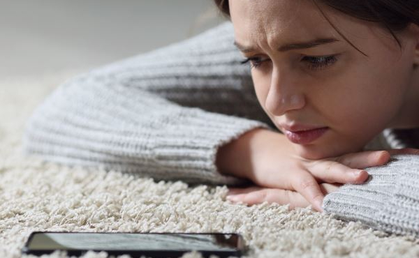 Teenage girl lying on the floor looking at a mobile phone